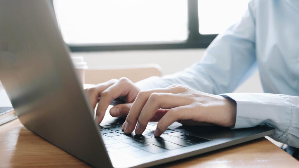 imagen de chico con camiza de mangas azul escribiendo en una laptop